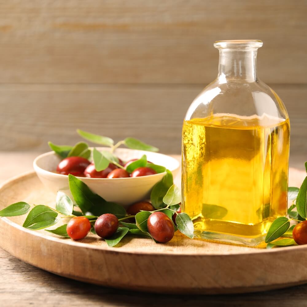 A medium size bottle with yellow liquid in it next to small red berries on a plate.