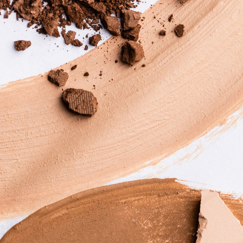 Makeup brown powder chunks on 2 different smears of makeup swatches.