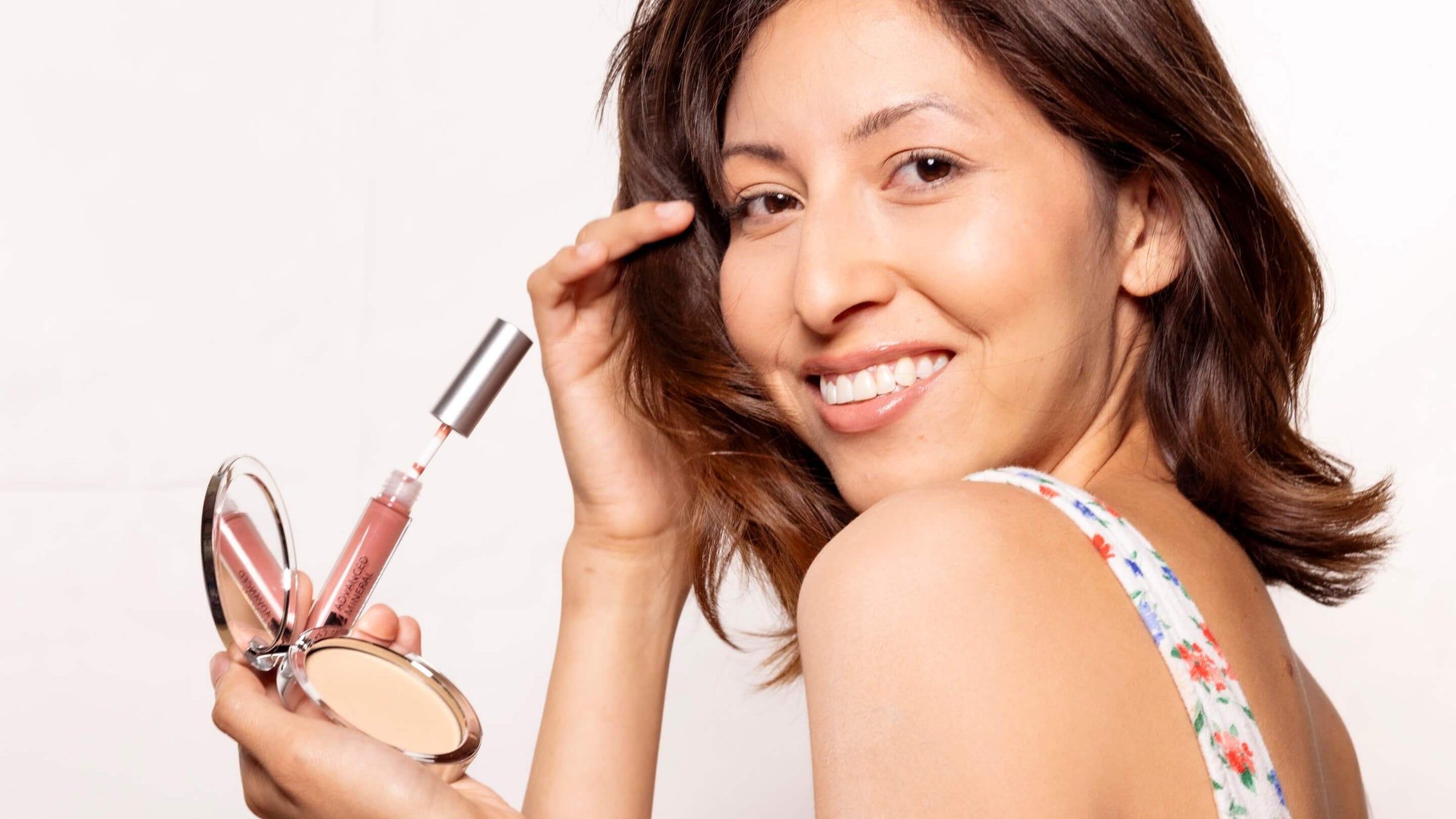 Woman applying lip gloss and concealer